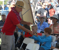 picture of volunteer handing ukes to three small boys